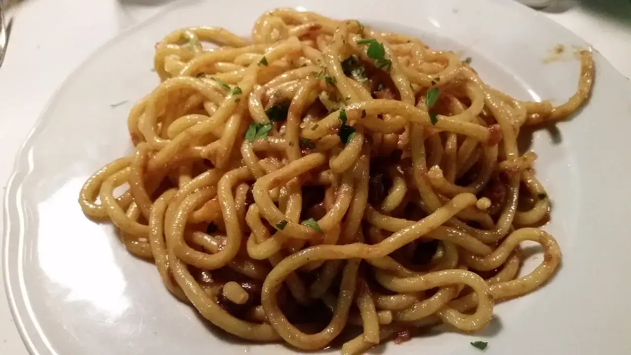 Un piatto di bigoli con le sarde, conditi con un sugo saporito e guarniti con prezzemolo fresco.