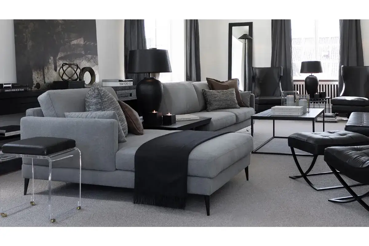 Grå soffa med inspiration från kuddar i olika texturer och färger. Mörka accenter som lampor och plädar ger en elegant känsla.