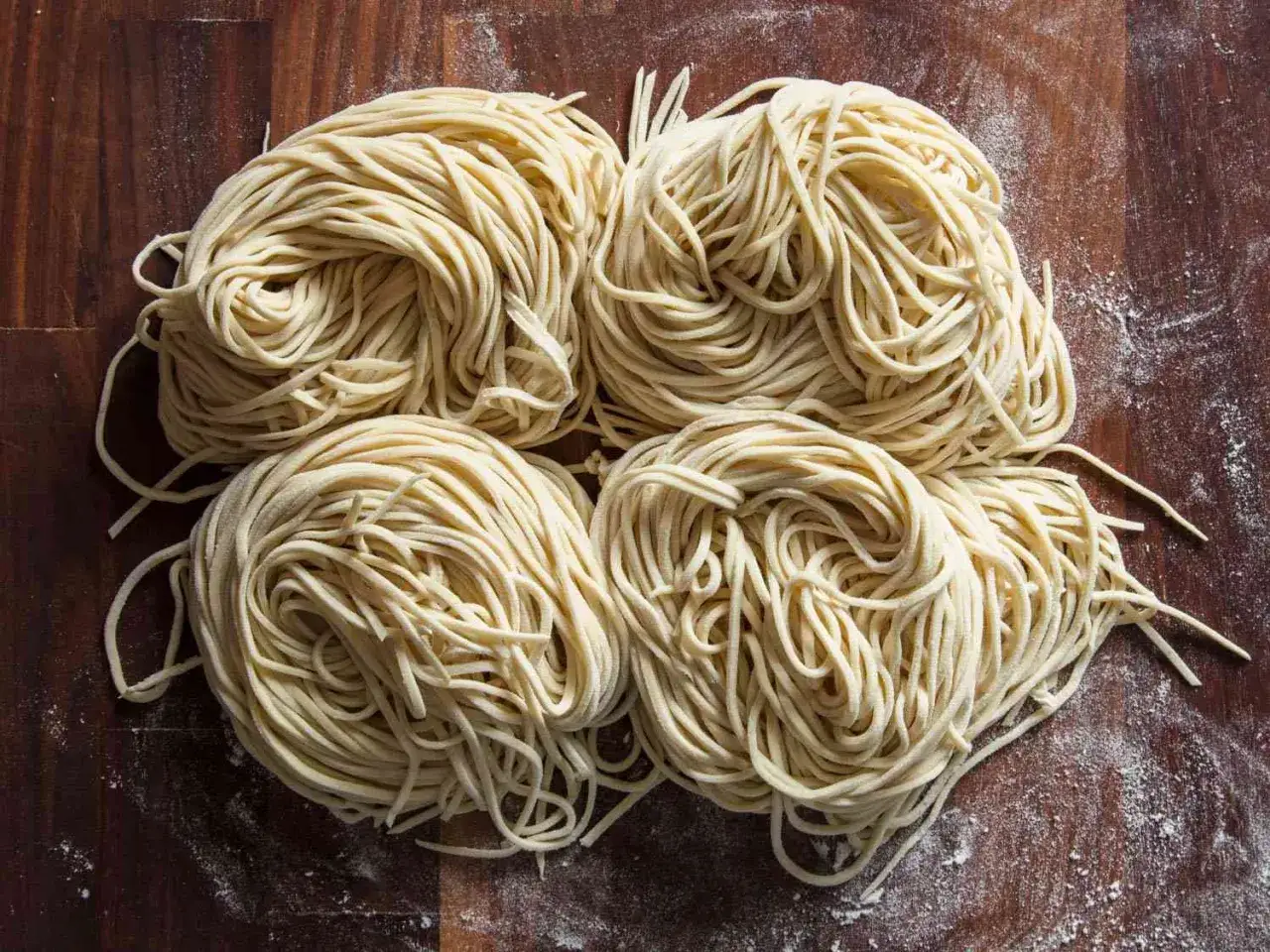 Vier Portionen frischer Ramen-Nudeln liegen auf einem Holztisch. Perfekt f&uuml;r dein n&auml;chstes Projekt, ramen selber machen!
