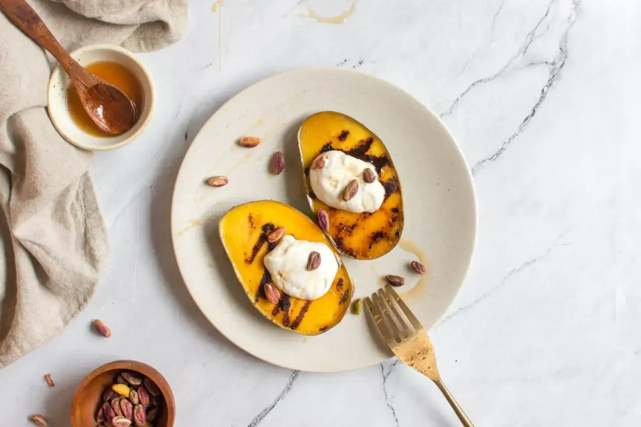 Grillad mango med kr&auml;mig topping, pistagen&ouml;tter och en ringlad honung. Honung nyttigt och gott till efterr&auml;tt.