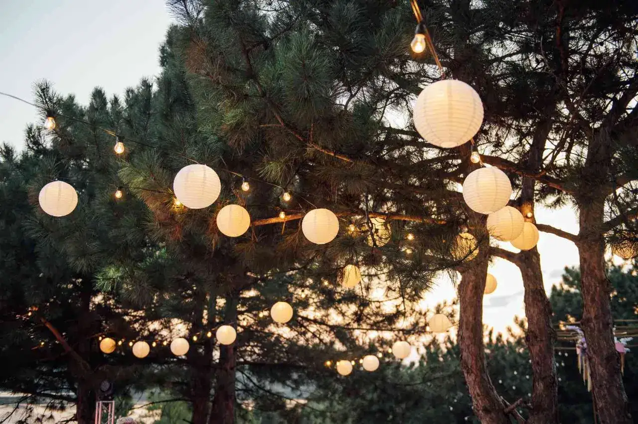 Girlandy z papierowych lampionów i żarówek tworzą magiczną atmosferę. Idealna jaka lampa do oświetlenia podwórka na letnie wieczory.