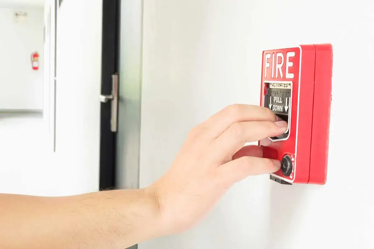 Mano activando la alarma de incendios, indicando c&oacute;mo apagar alarma de incendios.