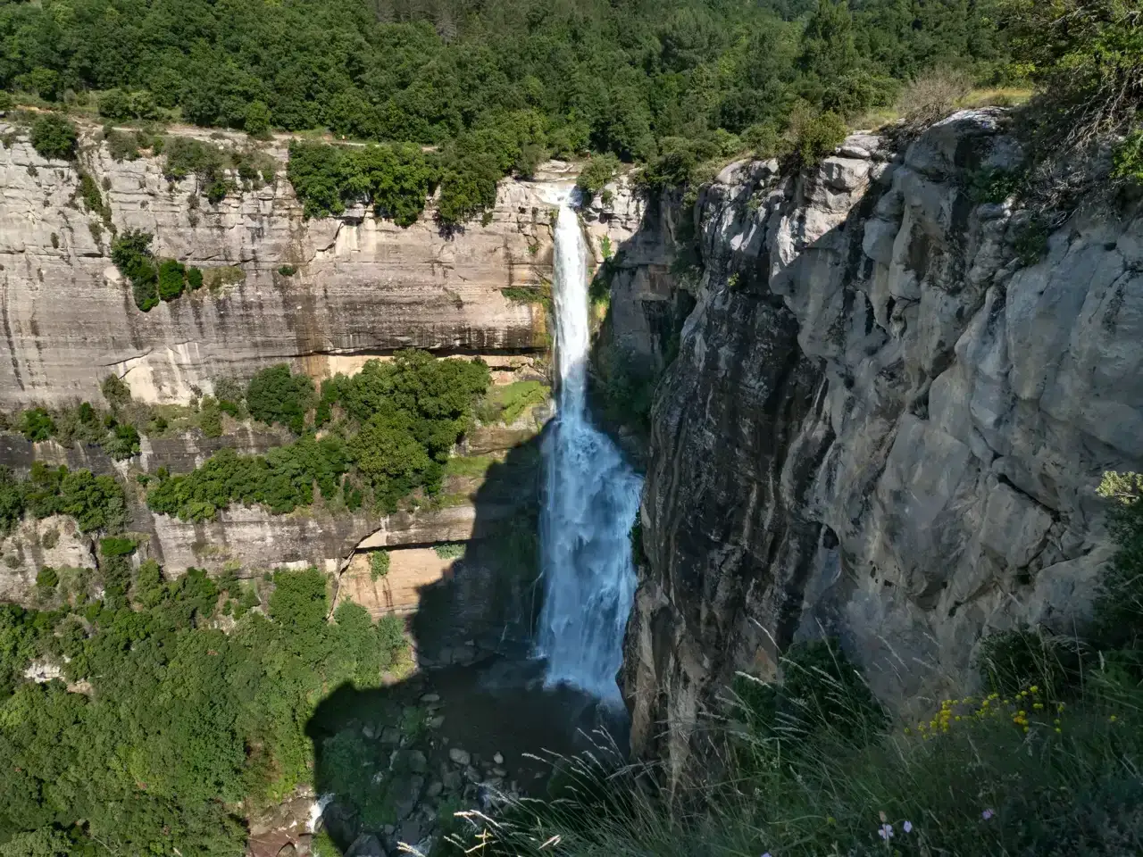Impresionante salto de agua en el salt de Sallent, cayendo por un acantilado rocoso cubierto de vegetaci&oacute;n exuberante.