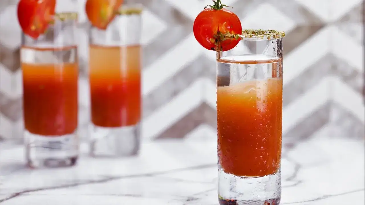 Orzeźwiający drink Wściekły Pies, ozdobiony pomidorkiem koktajlowym i ziołową posypką na brzegu szklanki.