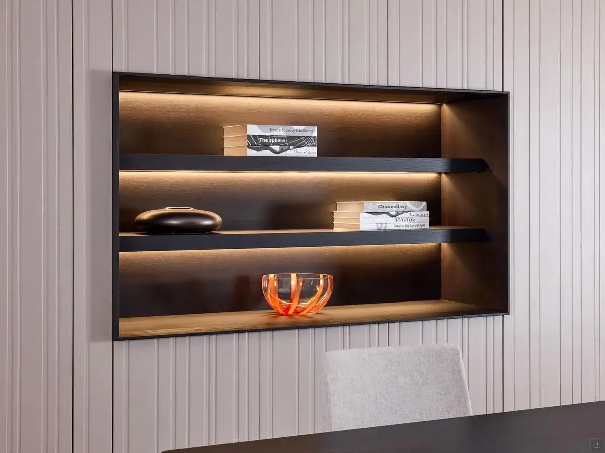 Elegante nicchia nel muro salotto con illuminazione soffusa, libri e oggetti decorativi.