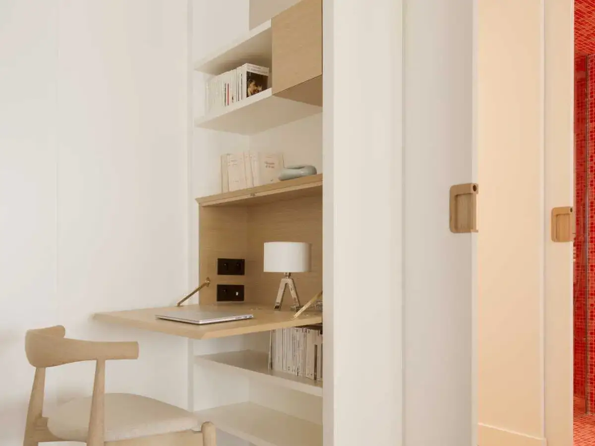 Un bureau placard mural en bois clair, avec une chaise assortie, un ordinateur portable et une lampe.