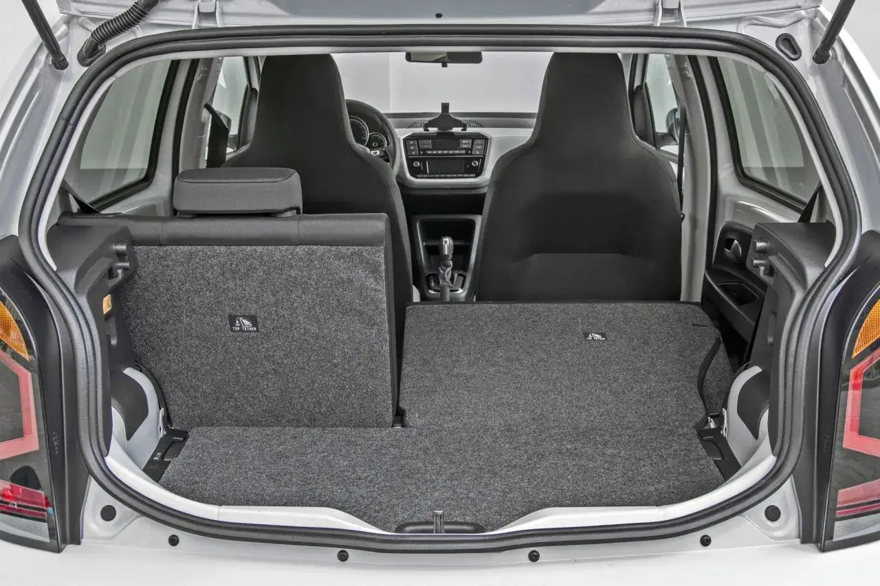 Bagażnik Volkswagen Up. Widok z tyłu na siedzenia i podłogę bagażnika. Wady tego modelu to m.in. ograniczona przestrzeń.