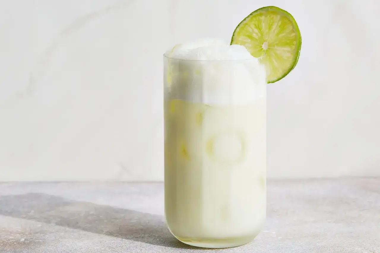 Erfrischende brasilianische Limonade mit viel Schaum und einer Limettenscheibe garniert, serviert in einem hohen Glas mit Eis.