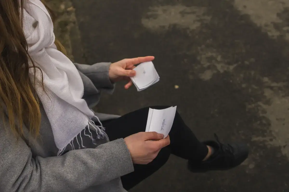 Une femme en manteau gris et écharpe blanche tient des notes pour un rattrapage mémoire.