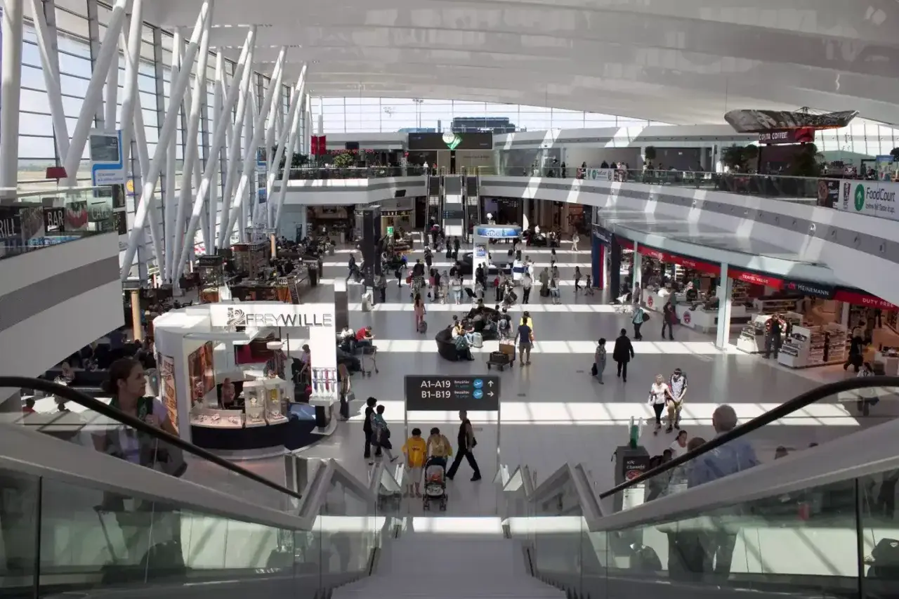 Tętniący życiem terminal lotniska w Budapeszcie, z ludźmi przemieszczającymi się między sklepami i kawiarniami.