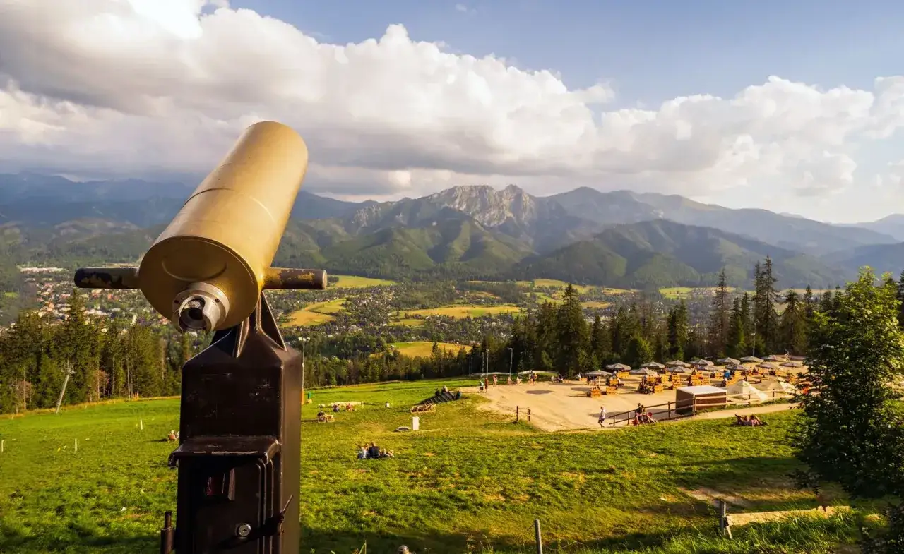 Widok z Gubałówki na Tatry. Lornetka zaprasza do podziwiania malowniczej trasy i górskiego krajobrazu.