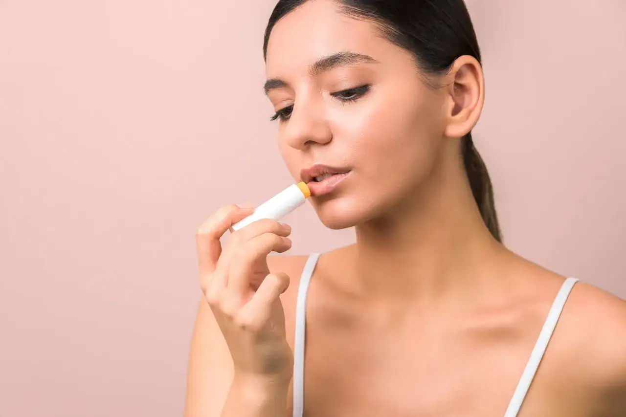 Mujer aplicándose bálsamo con retinol en los labios para un cuidado intensivo.