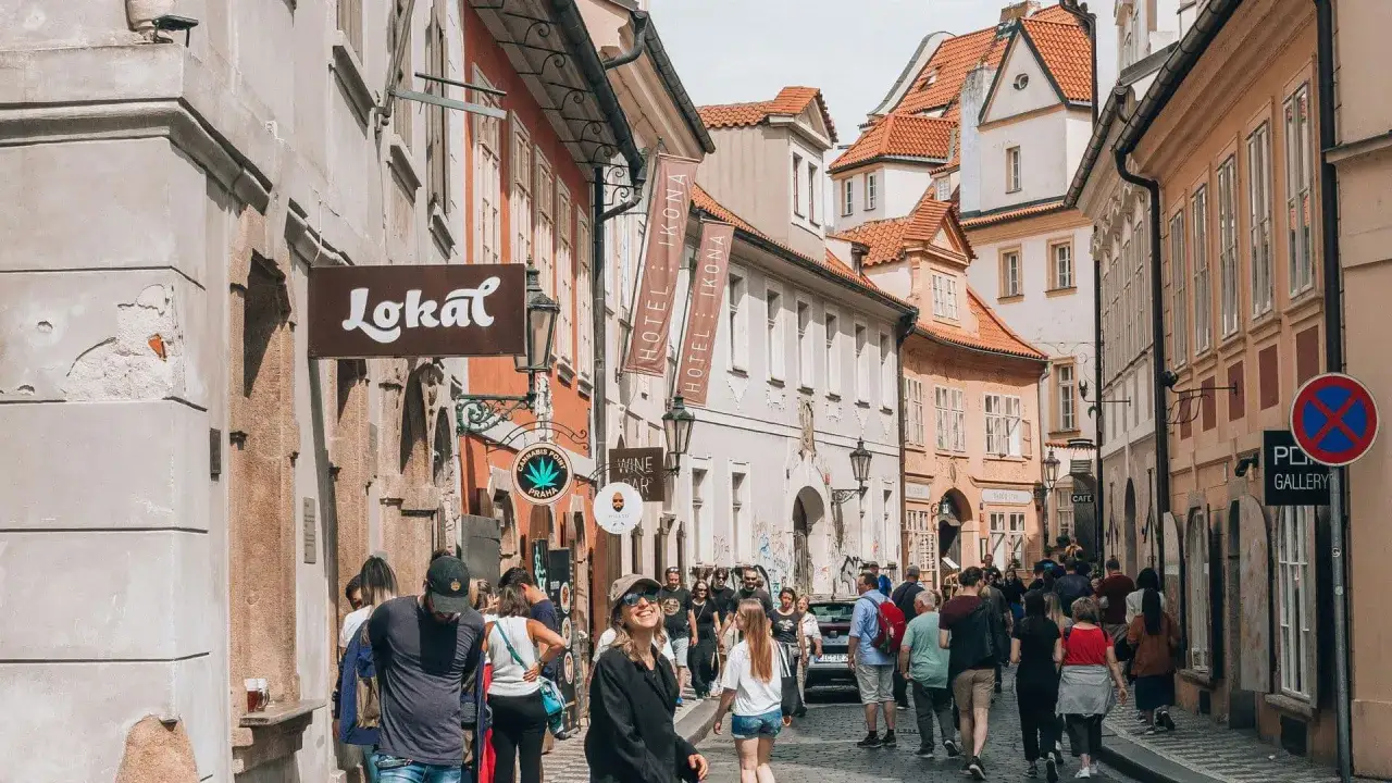 Praga, Czechy, gdzie warto pojechać! Tłum ludzi spaceruje wąską uliczką z szyldami