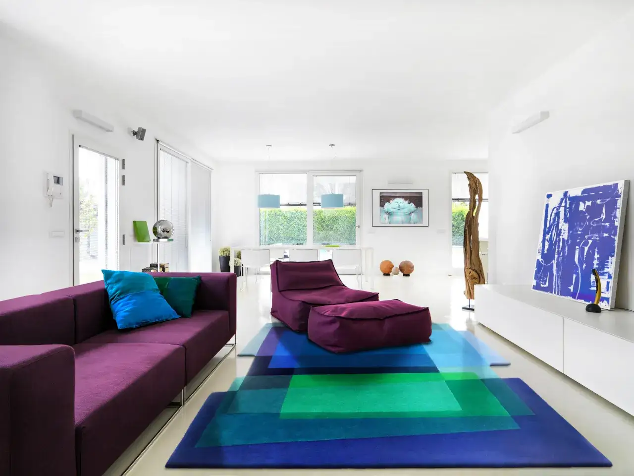 Modernes Wohnzimmer mit lila Sofa, Sitzsack und einem Teppich, der den Schall schlucken könnte.