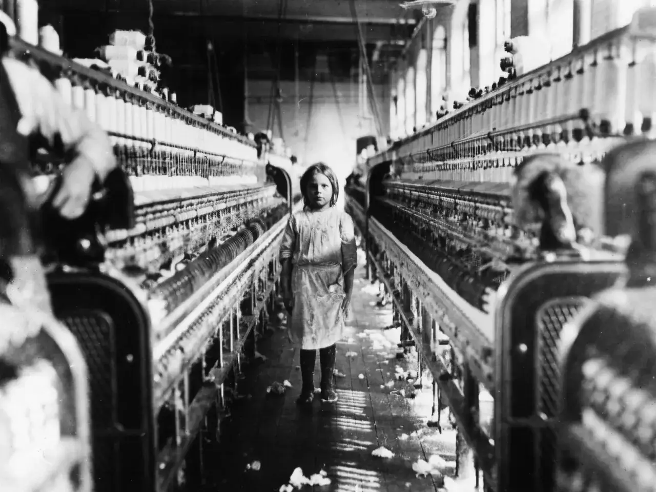 Ein junges M&auml;dchen steht in einer Fabrik zwischen Spinnmaschinen. Ein trauriges Zeugnis von Kinderarbeit in Deutschland.