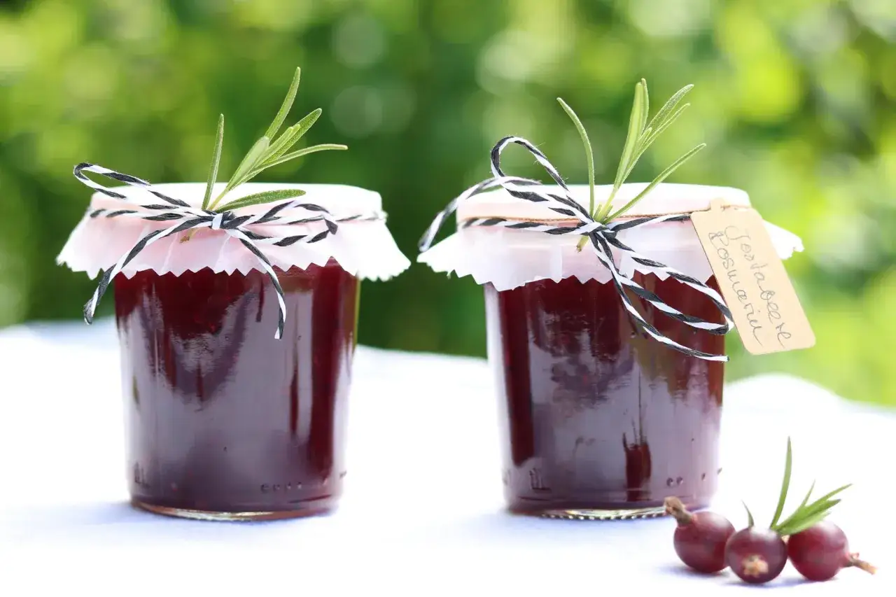 Zwei Gl&auml;ser hausgemachte Jostabeere Marmelade, verziert mit Rosmarin und Band. Ein Genuss f&uuml;r den Fr&uuml;hst&uuml;ckstisch.