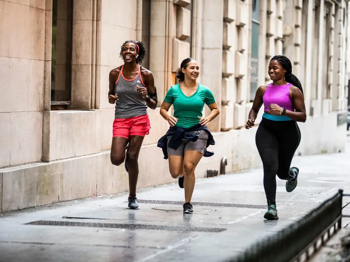 Drei Frauen genießen ihr **training laufen** auf einer städtischen Straße. Sie lachen und scheinen Spaß zu haben.