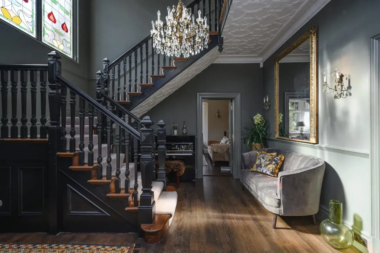 Peindre une cage d'escalier en noir profond met en valeur le lustre et le vitrail. Un choix audacieux pour un hall d'entrée élégant.