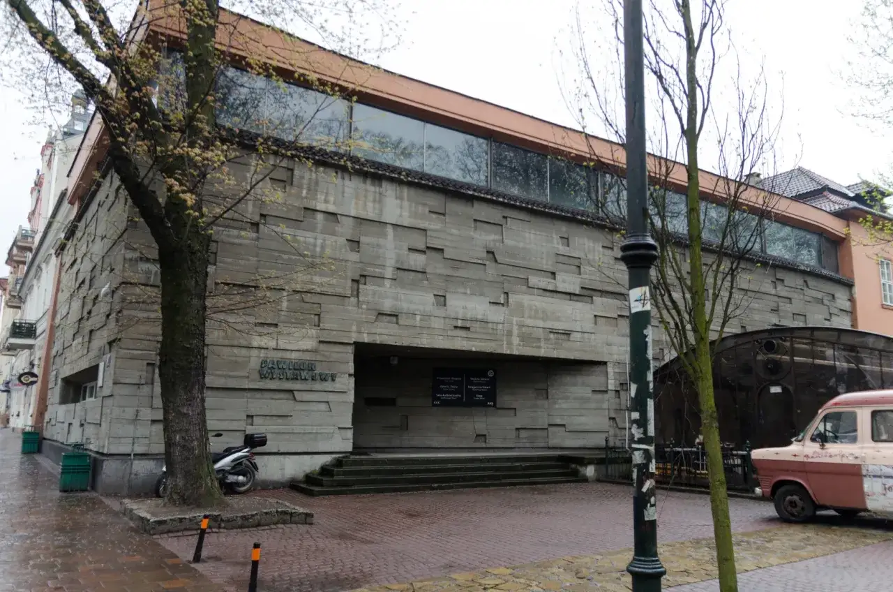 Pawilon Wystawowy, część Muzeum Sztuki Współczesnej Kraków, z betonową fasadą i drzewem przed wejściem.