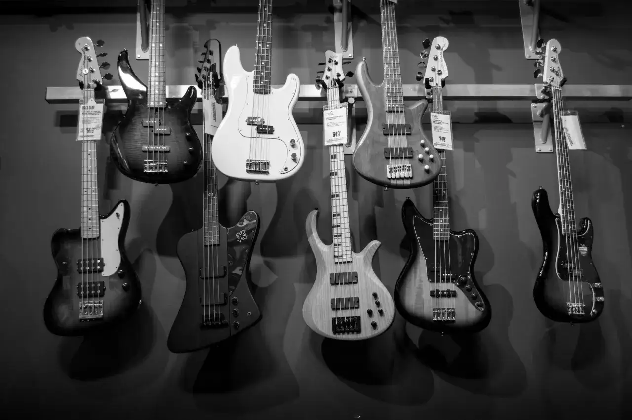 Rząd gitar basowych w sklepie muzycznym. Różnorodne modele, kolory i kształty tworzą imponujący zestaw basowy.