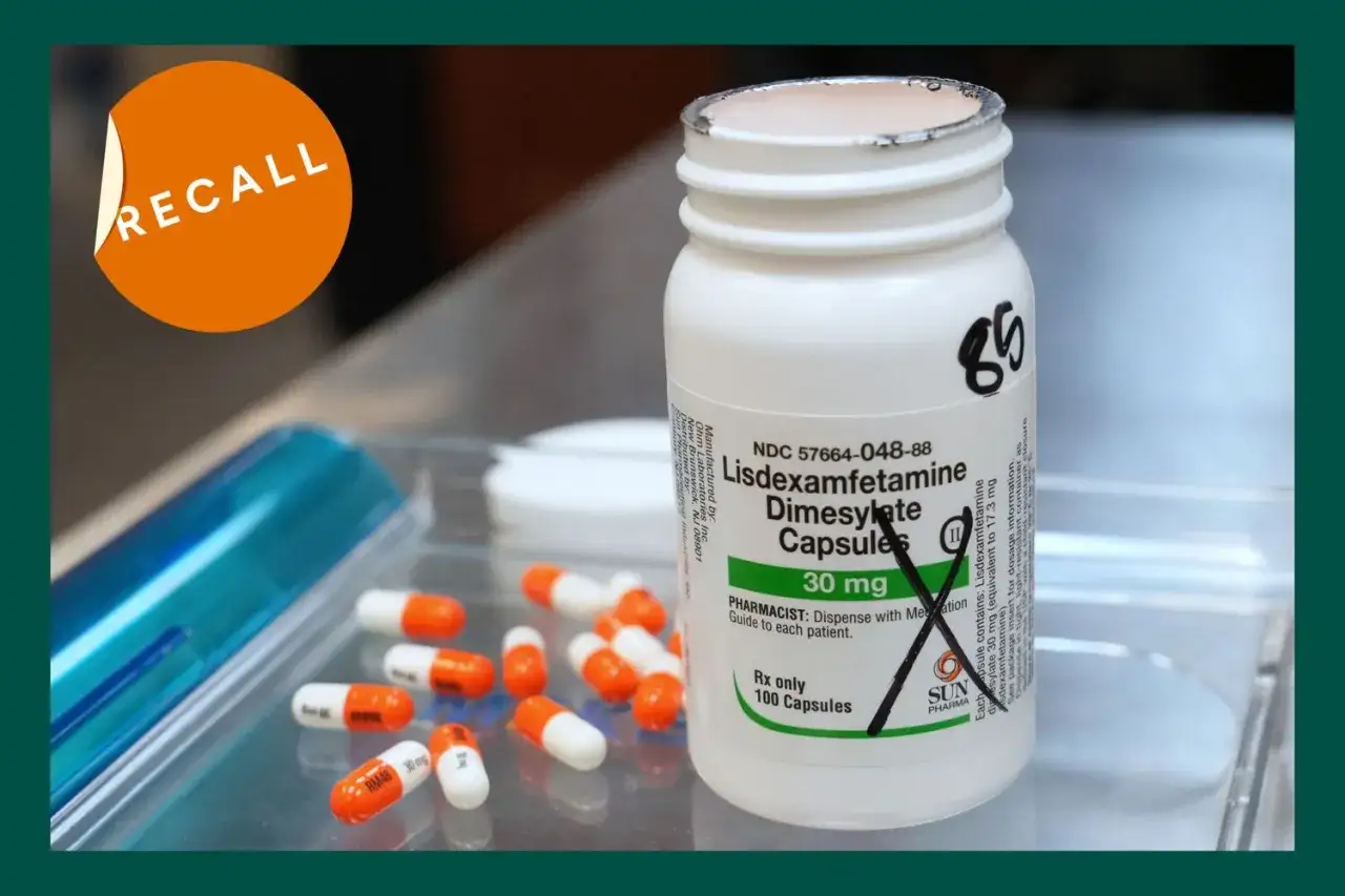 Napis na butelce to Lisdexamfetamine Dimesylate Capsules 30 mg, znane jako Elvanse. Pomarańczowo-białe kapsułki leżą obok, a na górze widnieje naklejka 