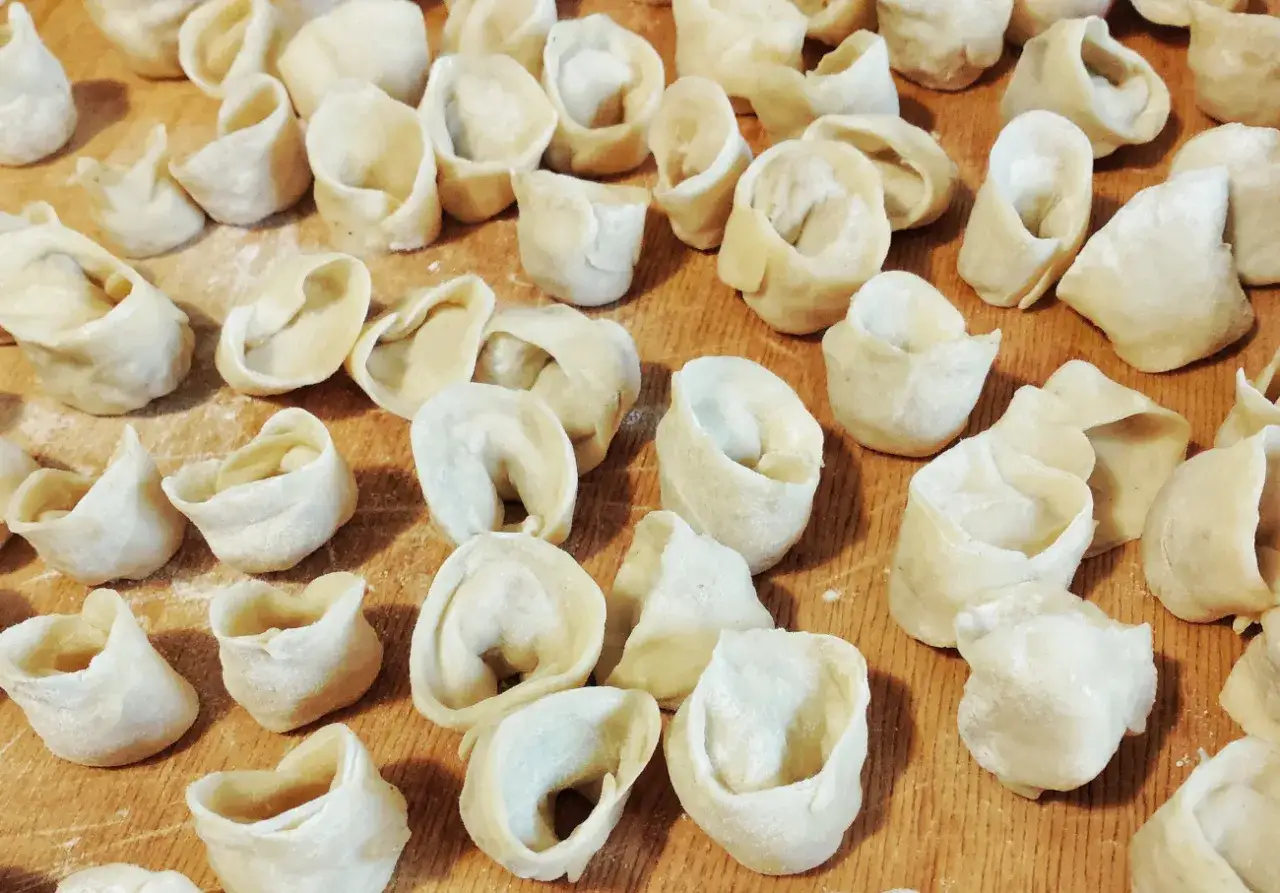 Gotowe do gotowania pierogi leżą na drewnianej desce. Zastanawiasz się, ile gotować pierogi, by były idealne?