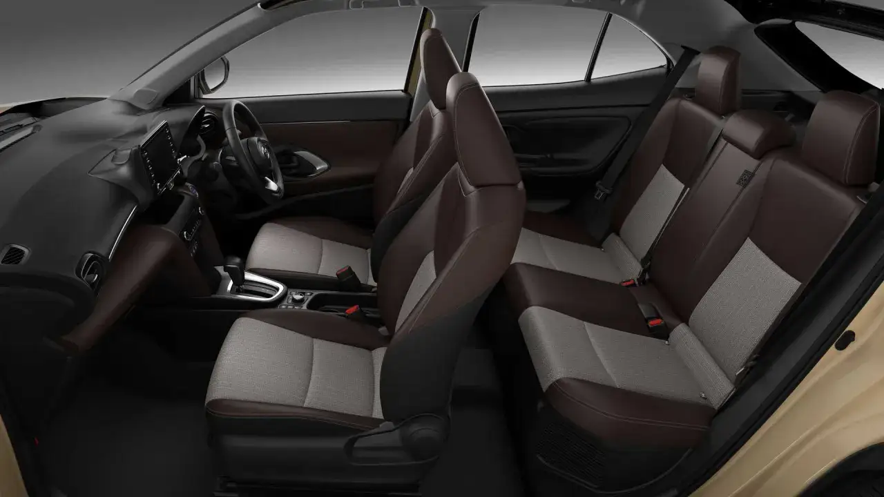 Wnętrze Toyoty Yaris Cross z brązowo-szarymi siedzeniami. Wady tego modelu mogą dotyczyć np. ograniczonej przestrzeni z tyłu.