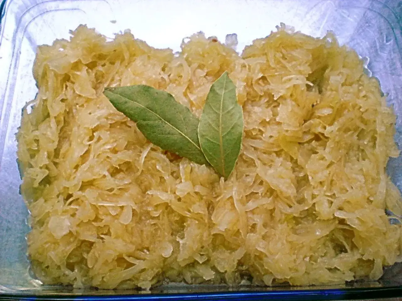 Sauerkraut kochen nach Omas Rezept: Ein Glas mit frisch gekochtem Sauerkraut, garniert mit zwei Lorbeerblättern.