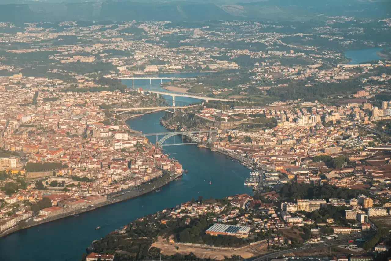 Widok z lotu ptaka na miasto Porto, z rzeką Duero przecinającą krajobraz i licznymi mostami.