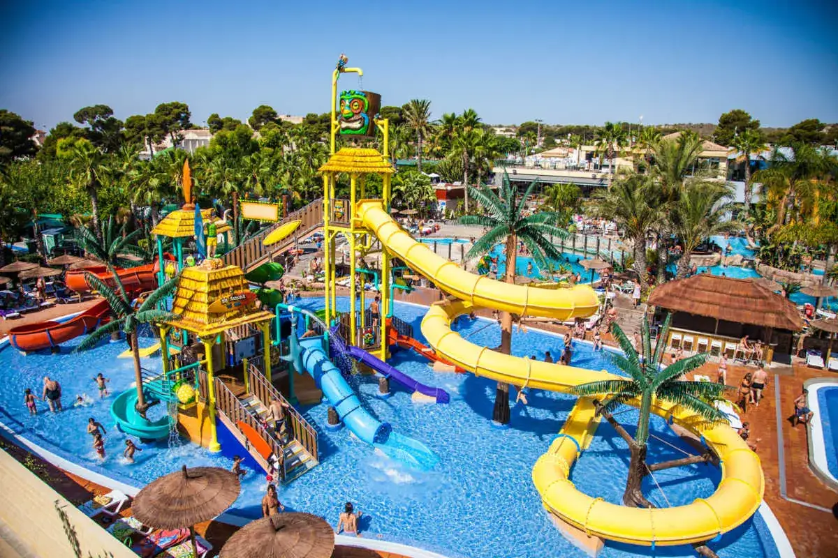 Un día de diversión en un parque acuático con toboganes en España. Familias disfrutan de las atracciones bajo el sol.
