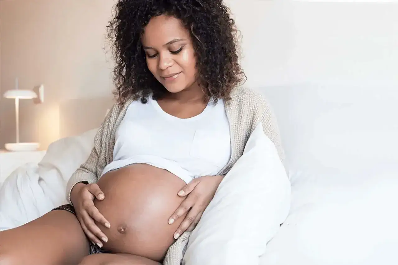 Femme enceinte caresse son ventre, sa peau est douce malgr&eacute; la grossesse.