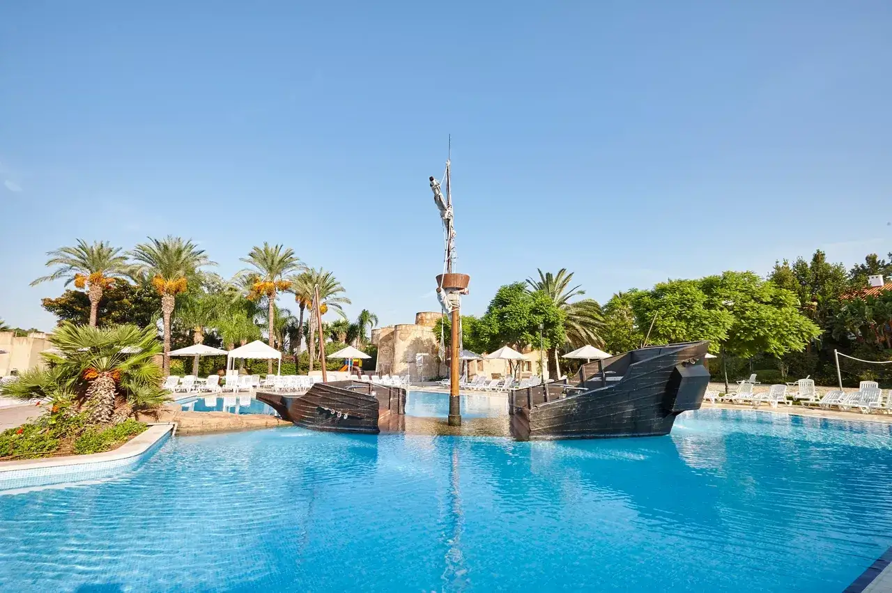 Piscina con barco pirata y palmeras en el hotel El Paso PortAventura.