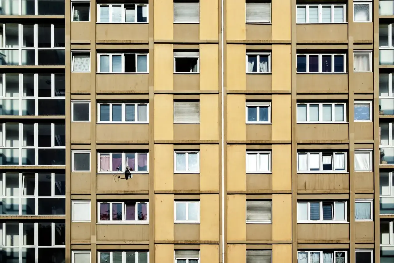 Wielopiętrowy blok mieszkalny z wieloma oknami. Czy wojsko daje mieszkanie? Tu mieszkają ludzie, nie żołnierze.