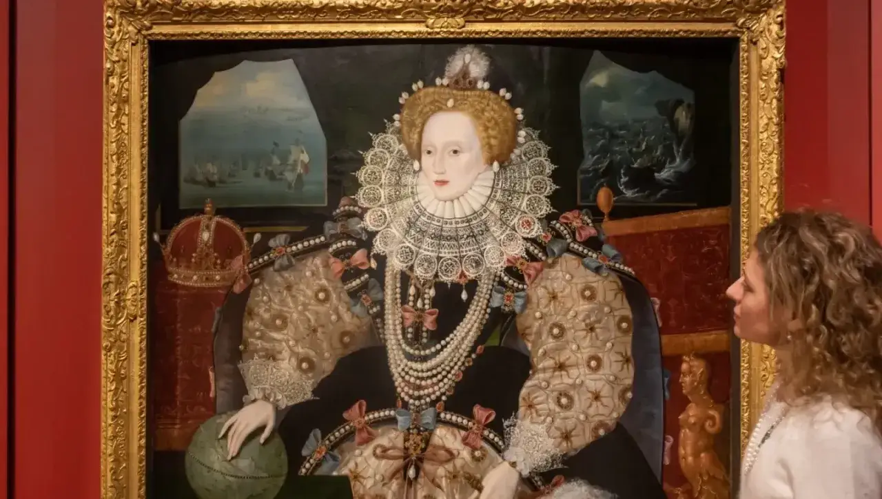 A woman gazes at a grand queen Elizabeth portrait, adorned in pearls and a ruff, holding a globe.