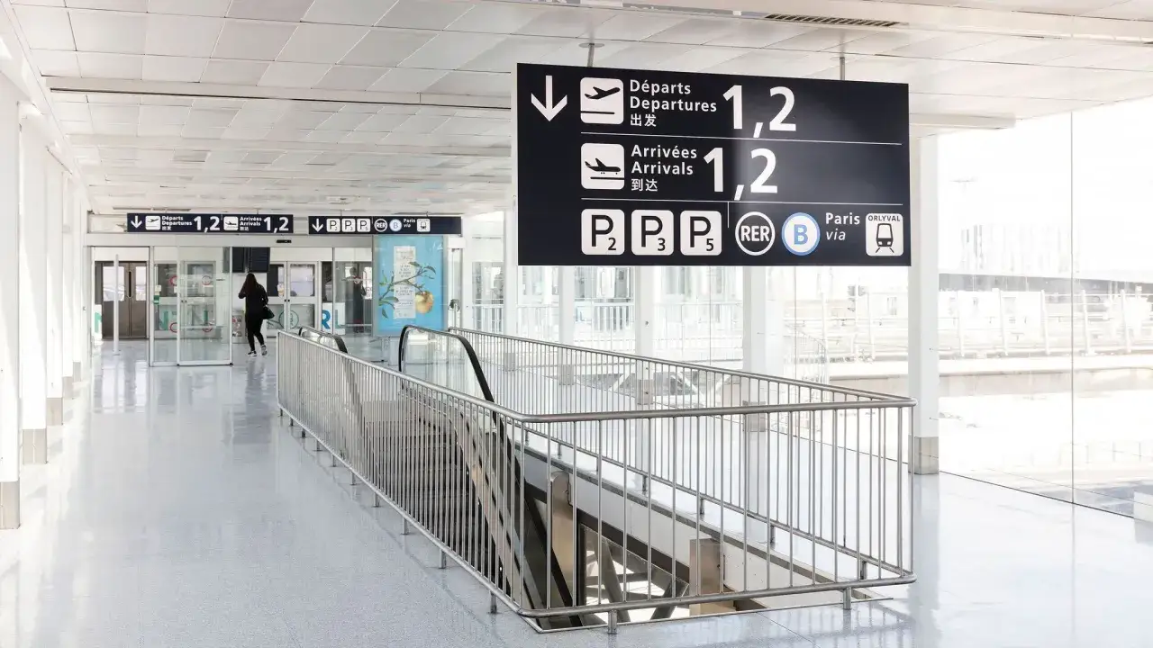 Panneau d'aéroport indiquant les départs, arrivées, parkings et le transport pour Orly via RER B.