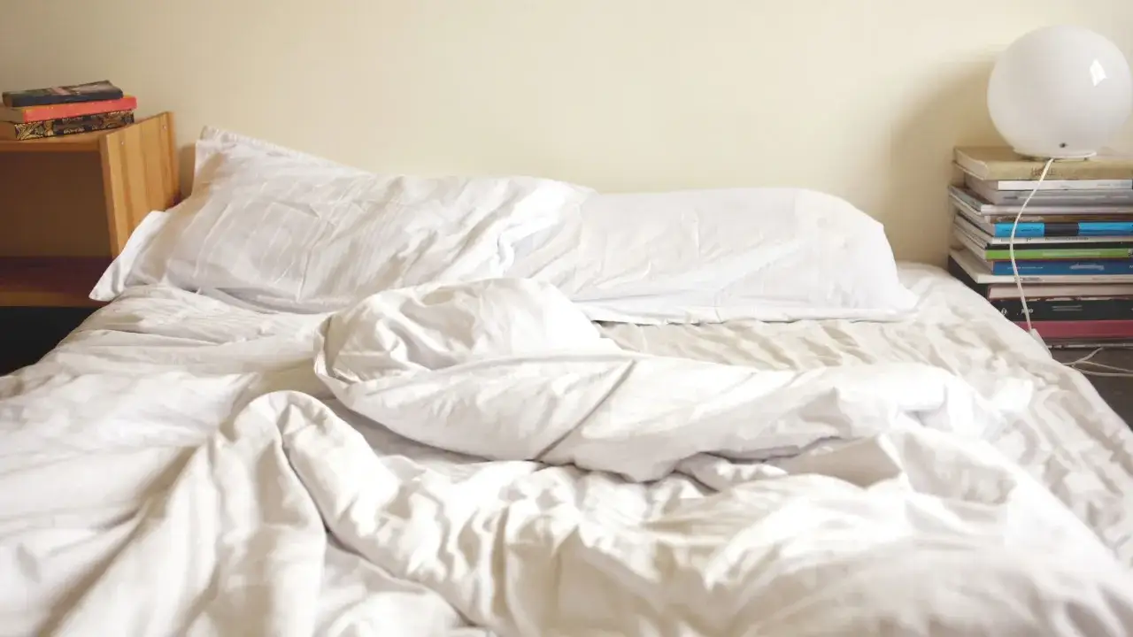 A rumpled white bed with pillows. Wondering if vinegar kills dust mites? This clean bedding might be the answer.
