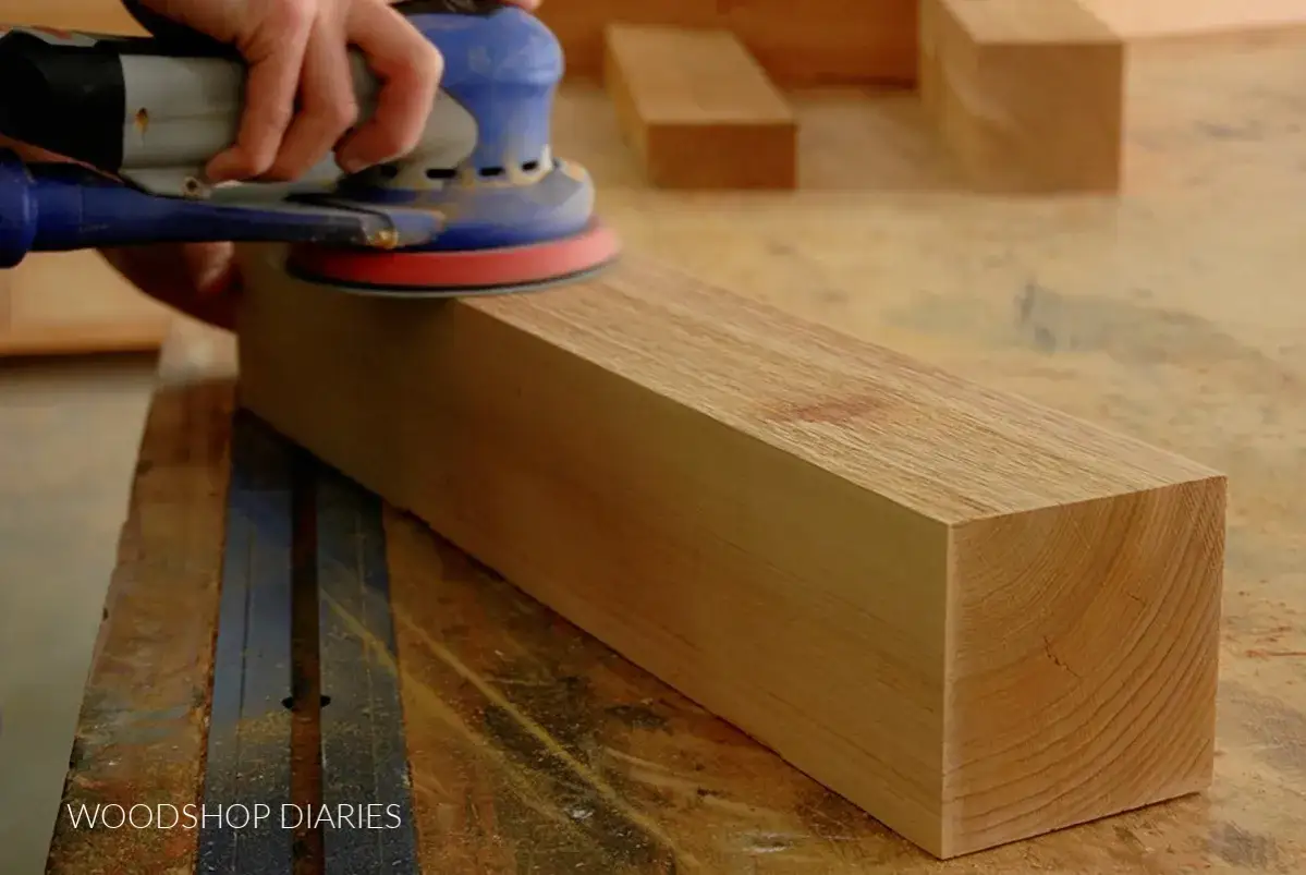 Levigatura di un pezzo di legno grezzo con una levigatrice orbitale. Il **trattamento legno grezzo** &egrave; fondamentale per prepararlo.