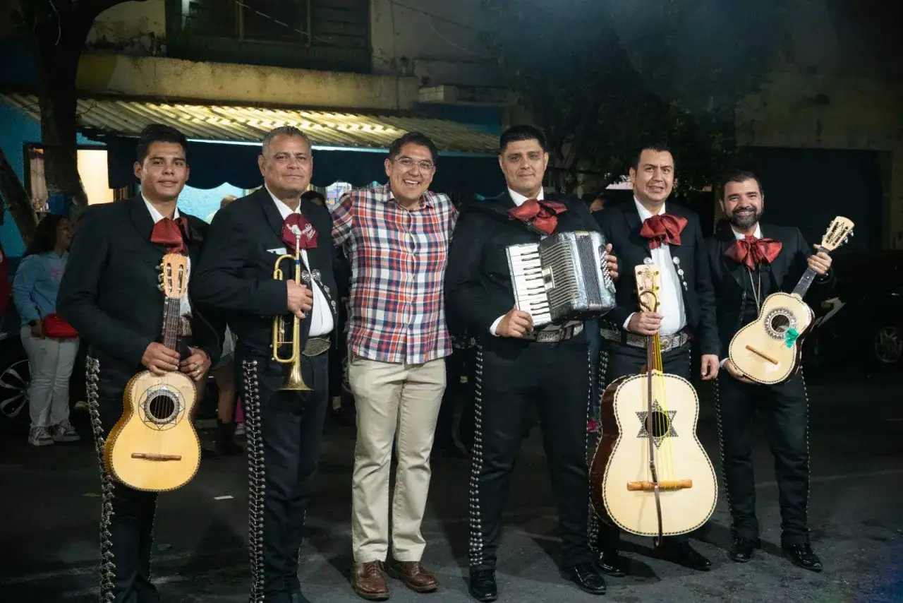 Zespół mariachi w tradycyjnych strojach, gotowy do występu. Muzycy trzymają gitary, trąbkę i akordeon.
