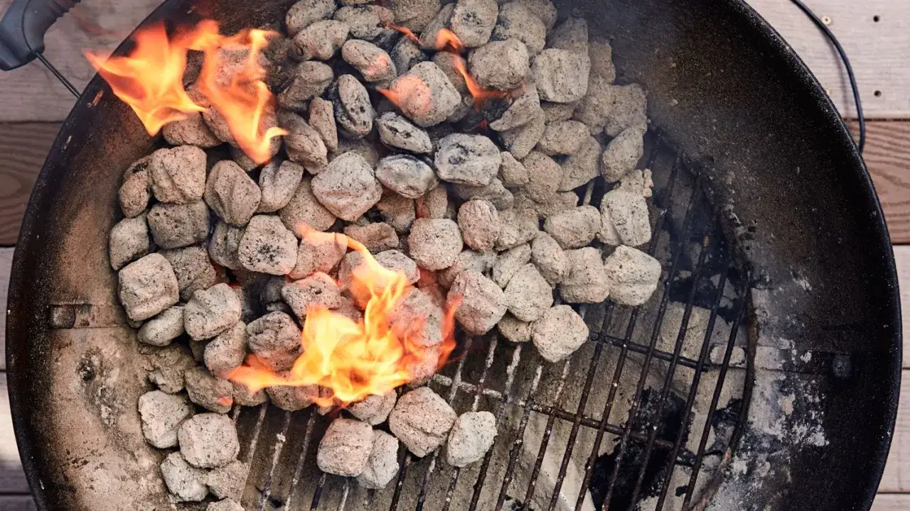 Braises de charbon incandescentes et flammes vives dans un barbecue, prêtes pour la cuisson.