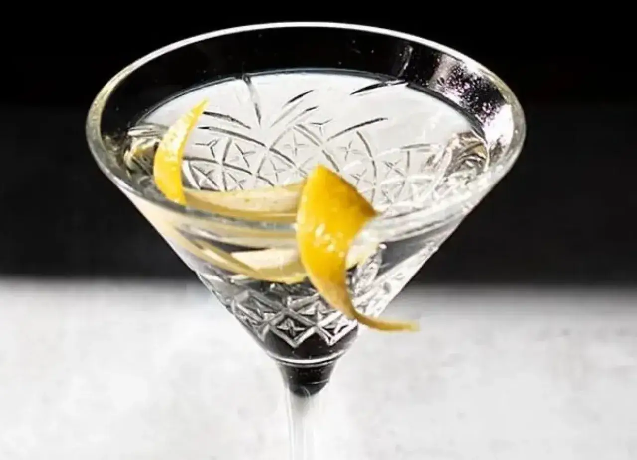 Ett elegant kristallglas med en klar vodka drink, garnerad med en citronskal. Perfekt för en sofistikerad kväll med vodka drinkar.