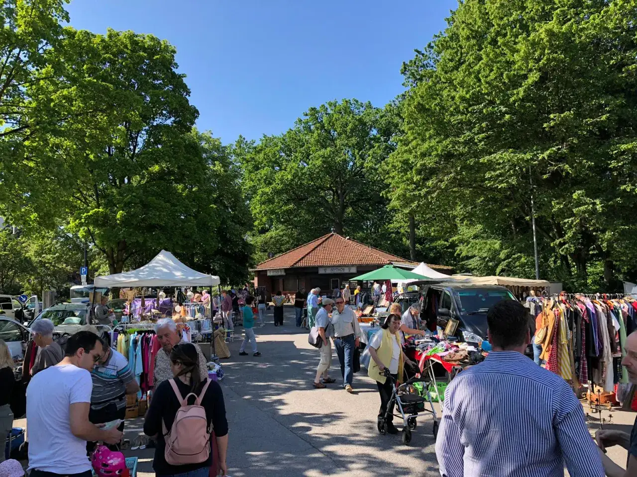 Bunter Tr&ouml;delmarkt in Refrath mit vielen St&auml;nden, Kleidung und Menschen unter B&auml;umen.