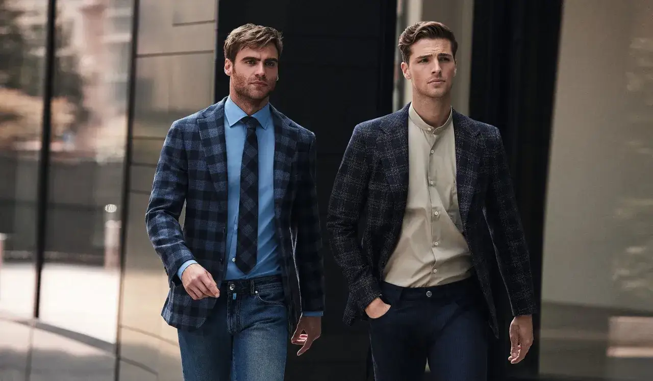 Two men walk in a city, showcasing stylish mens dressy casual outfits with blazers and jeans.