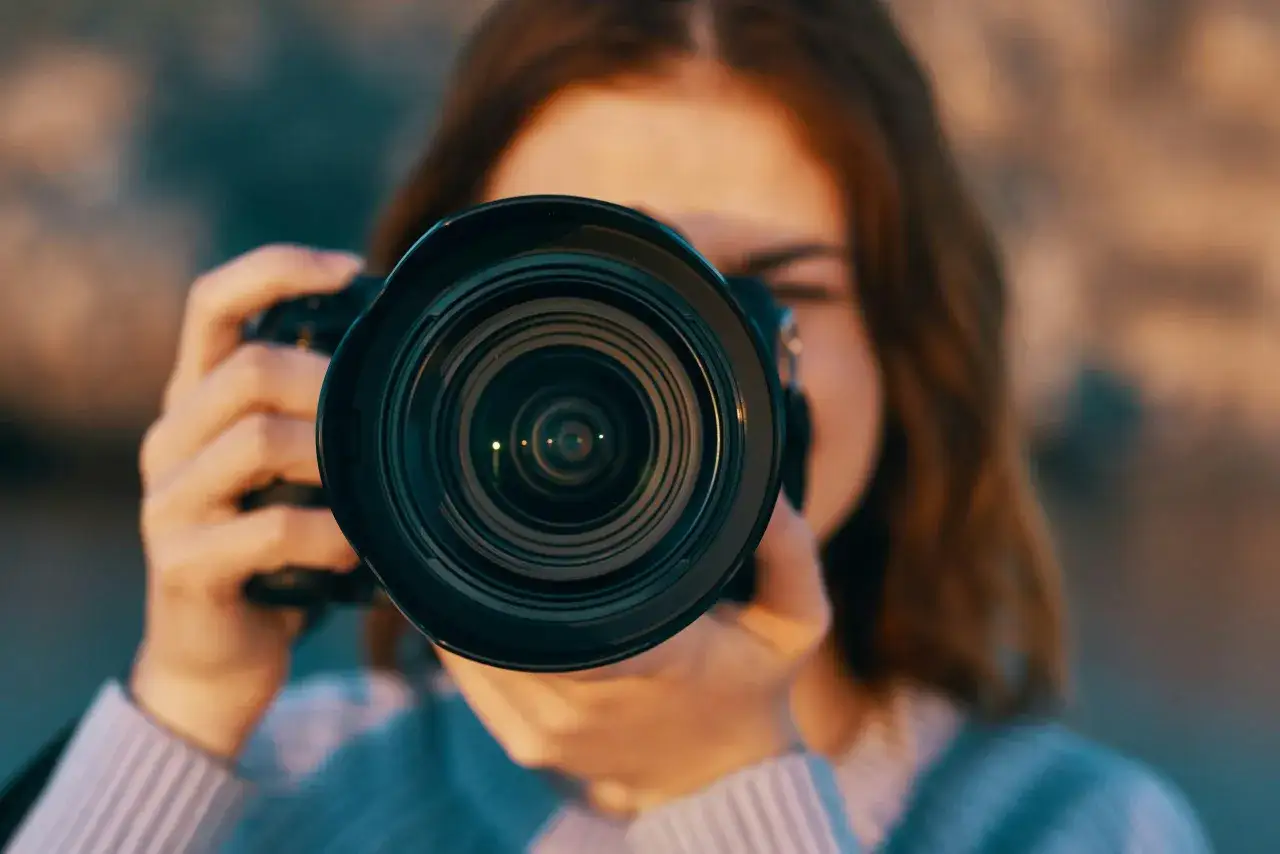 En person h&aring;ller upp en kamera och tittar genom s&ouml;karen. Linsen &auml;r i f&ouml;rgrunden, och det &auml;r tydligt vad betyder fokus f&ouml;r fotografen.