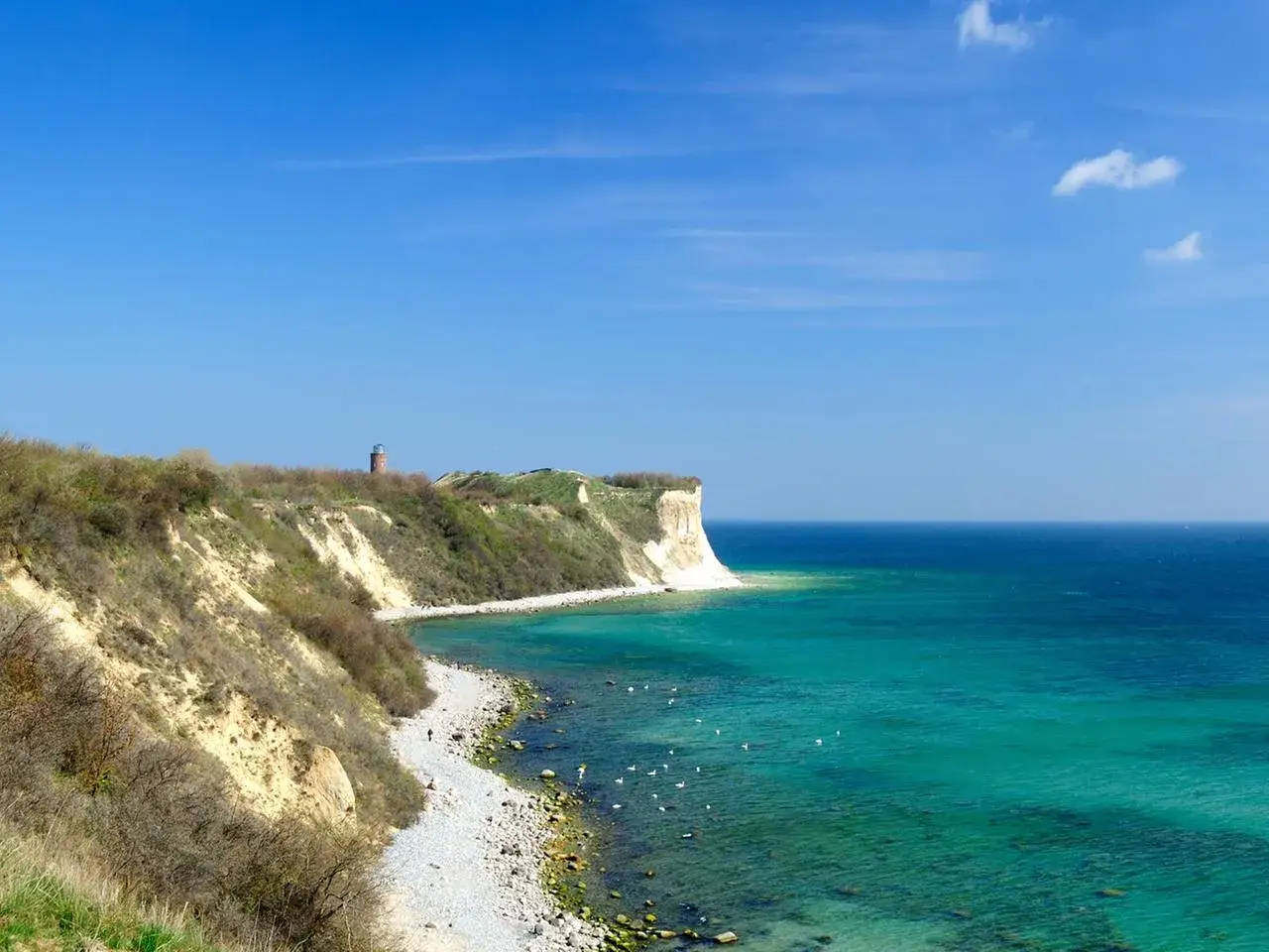 Steilküste bei Kap Arkona mit Leuchtturm, Kiesstrand und türkisfarbenem Meer.