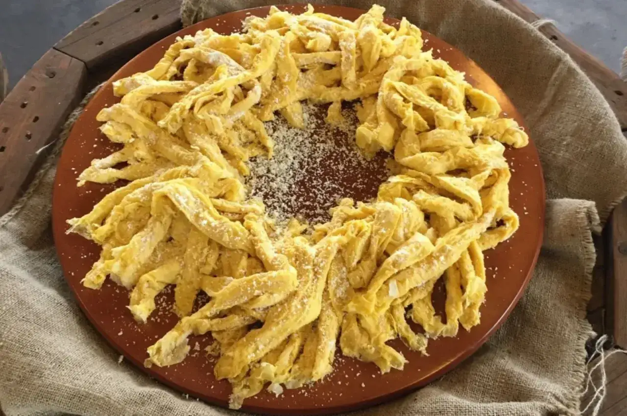 Frittelloni di Civita Castellana, pasta fresca fatta in casa, disposta a corona su un piatto di terracotta, cosparsa di formaggio grattugiato.