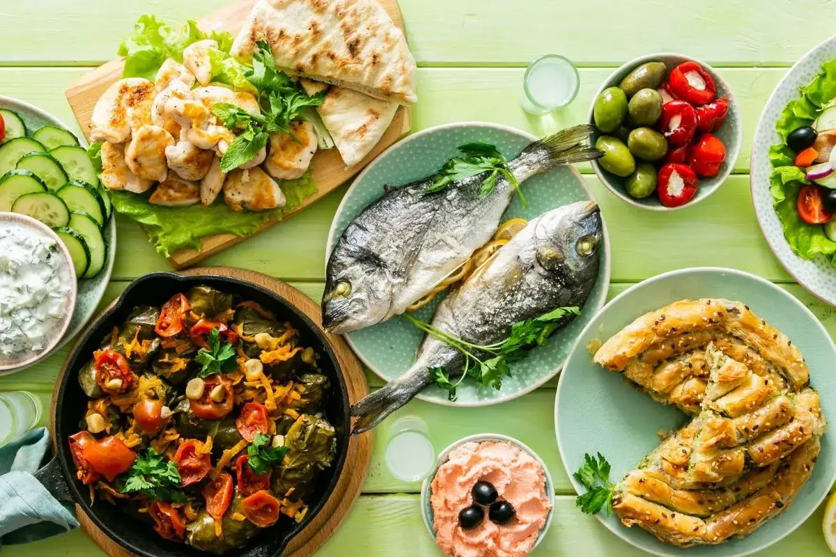 Kolorowy stół pełen smaków: ryby, kurczak, sałatka, oliwki, pieczone warzywa i ciasto filo. Idealne dieta śródziemnomorska przepisy.