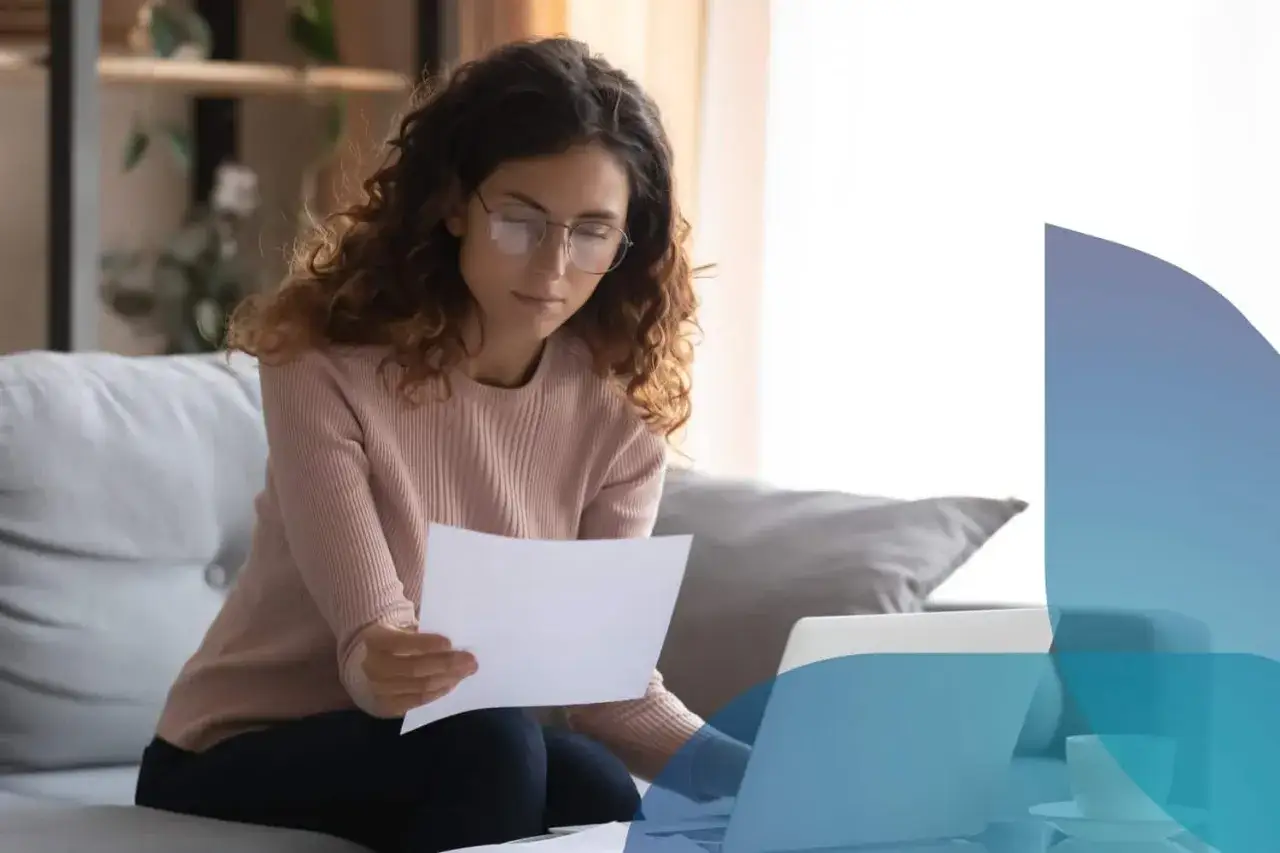 Donna con occhiali legge documenti al computer, affrontando la voltura utenze senza residenza.