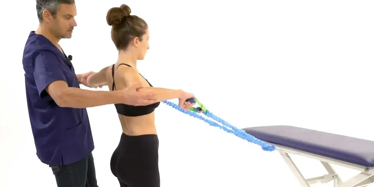 Un kin&eacute;sith&eacute;rapeute guide une femme dans des exercices de tendinite &eacute;paule avec un &eacute;lastique.