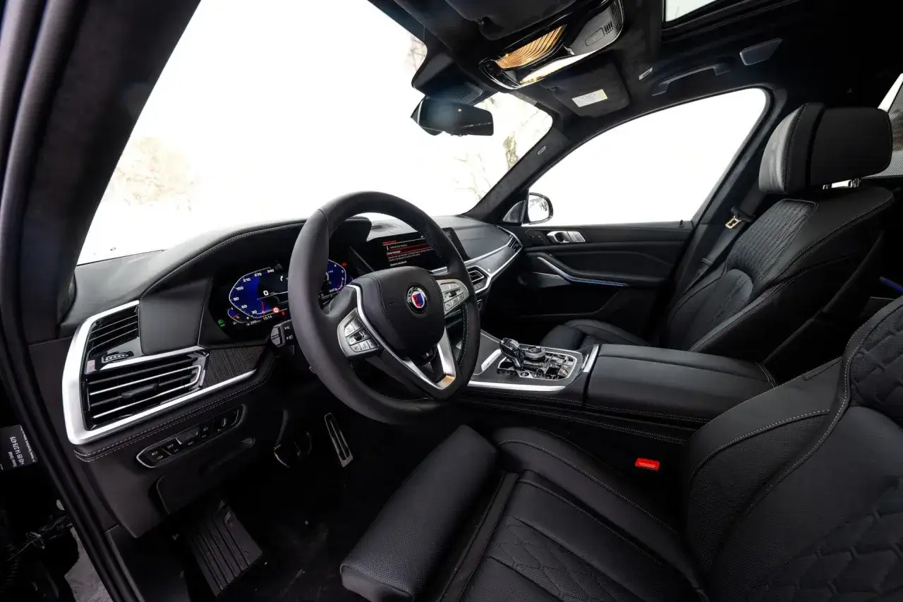Wnętrze luksusowego BMW Alpina z czarną, pikowaną tapicerką i nowoczesnym kokpitem.