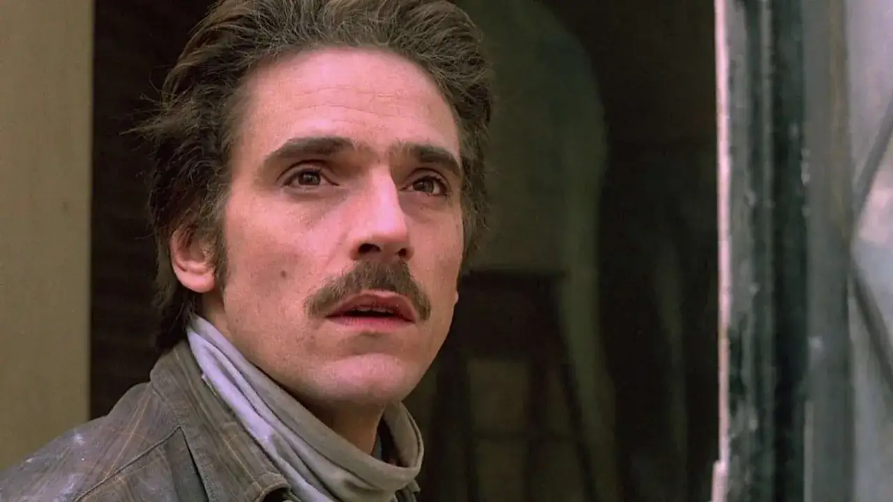 Jeremy Irons w filmach, z charakterystycznym wąsem i zmęczonym spojrzeniem, wygląda jak postać z dramatycznego filmu.